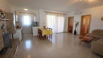 A spacious living area with a dining table, sofa, and kitchen in the background.