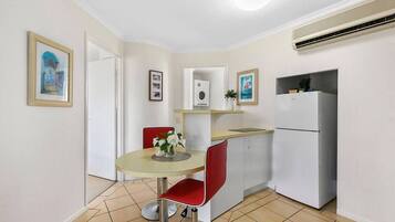 A compact kitchen with a dining table, chairs, a refrigerator, and a small countertop.