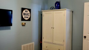 Ein Schlafzimmer mit einem Bett, einem Kleiderschrank, einem Fernseher und einem Schild mit der Aufschrift 'No Wake Zone' an der Wand.