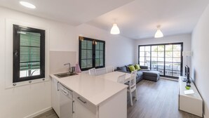 Una cocina moderna con una isla central, un comedor con sofá y ventanas amplias.
