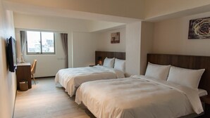 Hotellihuone, jossa on kaksi sänkyä, työpöytä ja ikkuna.
