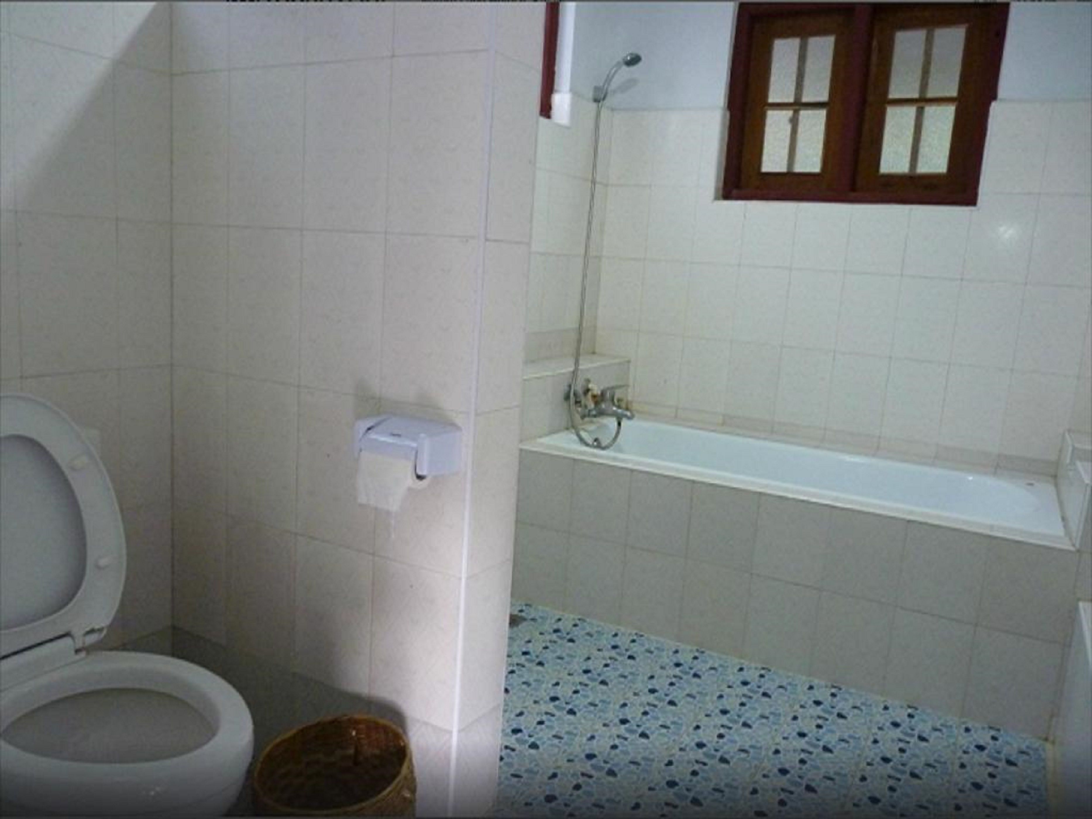 A bathroom with a toilet, a paper towel dispenser, a shower, and a bathtub.