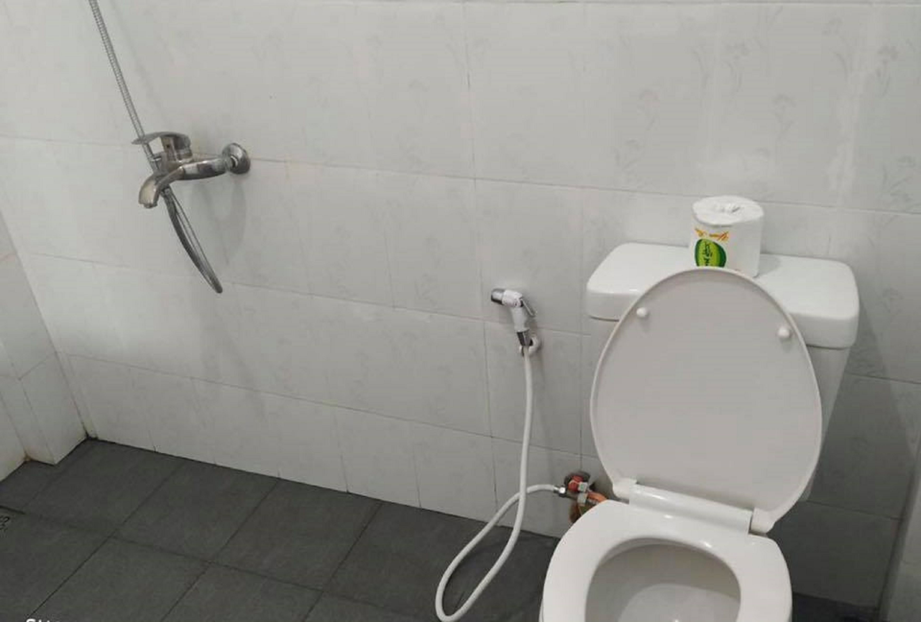 Un baño con inodoro, ducha y dispensador de papel higiénico.