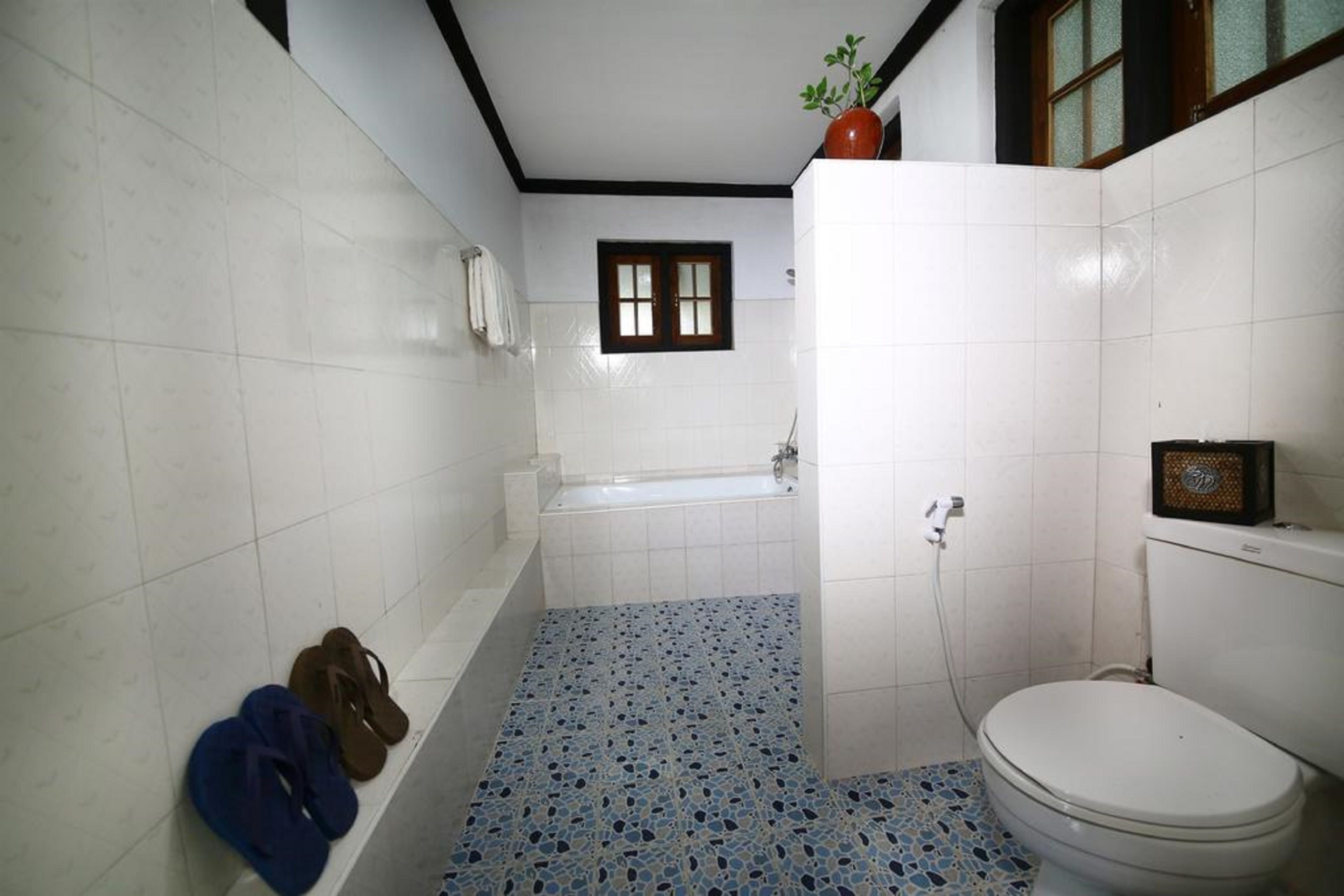 A bathroom with a bathtub, toilet, and a window.