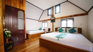 A bedroom with two beds, wooden flooring, a large wardrobe, and a sloped ceiling with skylights.
