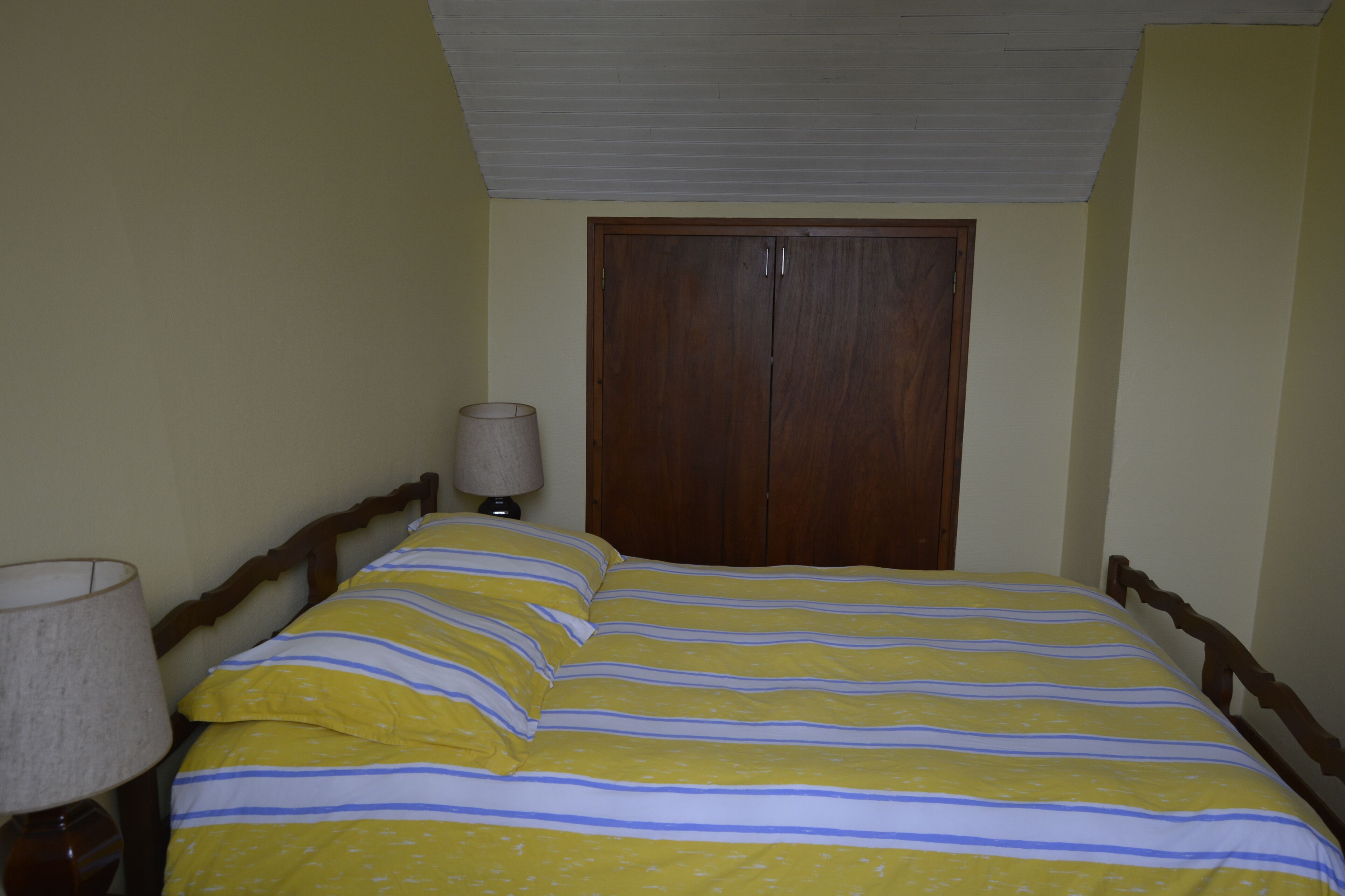 Ein Schlafzimmer mit einem Bett, einem Holzschrank und einer Nachttischlampe.