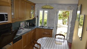 A kitchen with wooden cabinets, a microwave, a gas stove, and a dining table with chairs.