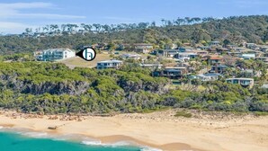 Una zona residencial costera con casas en una colina, una playa y una vista despejada del océano.