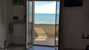 Une pièce dotée d’une porte-fenêtre coulissante donnant sur un balcon avec vue sur la mer.