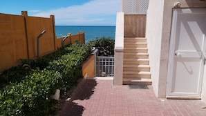 Un chemin pavé mène à un bâtiment d’où l’on a vue sur la mer.