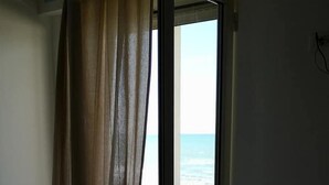 Une chambre avec un lit et une porte-fenêtre coulissante donnant sur un balcon avec vue sur la mer.