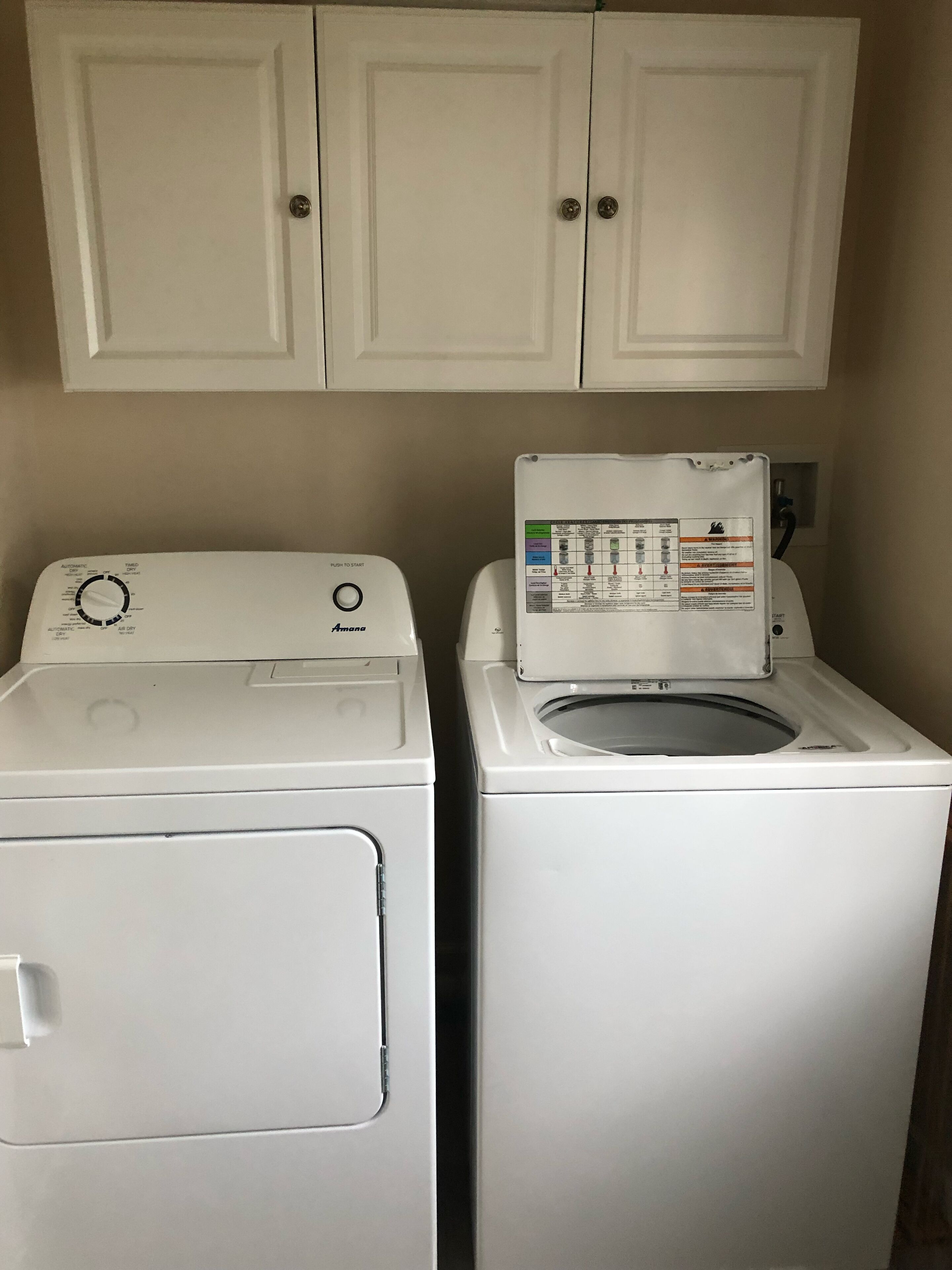 Un espace buanderie avec deux machines à laver blanches et un meuble de rangement au-dessus.