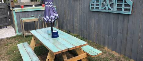 A picnic table with benches, an umbrella, and a decorative fence in a backyard.