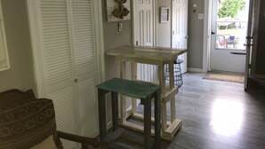 Un pasillo con un banco de madera, una puerta decorada con un adorno navideño y vistas al exterior.