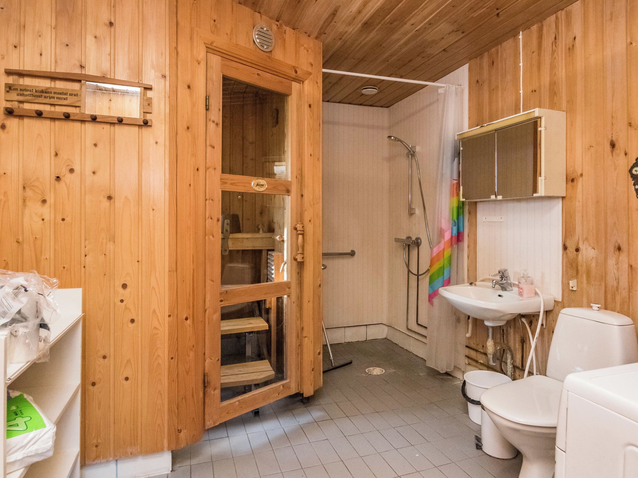 Puisesta materiaalista valmistettu kylpyhuone, jossa on suihku, wc ja lasiovilla varustettu puinen kaappi.