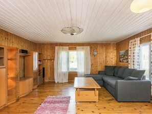 A wooden-paneled room with a sofa, a wooden table, and a cabinet. - Matkonranta by Interhome (Kerimäki)
