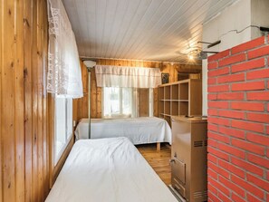 A room with two beds, wooden walls, a brick wall, and a window with curtains. - Matkonranta by Interhome (Kerimäki)