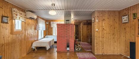 A room with wooden walls, a brick fireplace, a bed, a desk, and a chair.