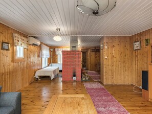 Ein Zimmer mit Holzwänden, einem Kamin aus Backsteinen, einem Bett, einem Schreibtisch und einem Stuhl.