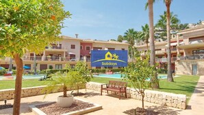 A resort with a sign for 'Solidays', a pool area, and a building with balconies.