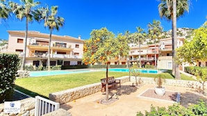 A resort with a swimming pool, palm trees, and a well-maintained lawn.