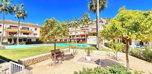 Un complexe hôtelier doté d’une piscine, de palmiers et d’une pelouse bien entretenue.