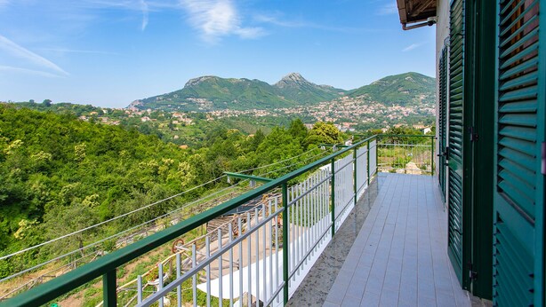 A balcony with a view of a mountainous landscape and a town below. - Mary's House, Agerola (Pianillo)