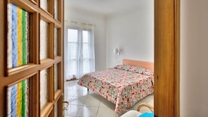 A bedroom with a bed, a nightstand, and a window with curtains. - Mary's House, Agerola (Pianillo)
