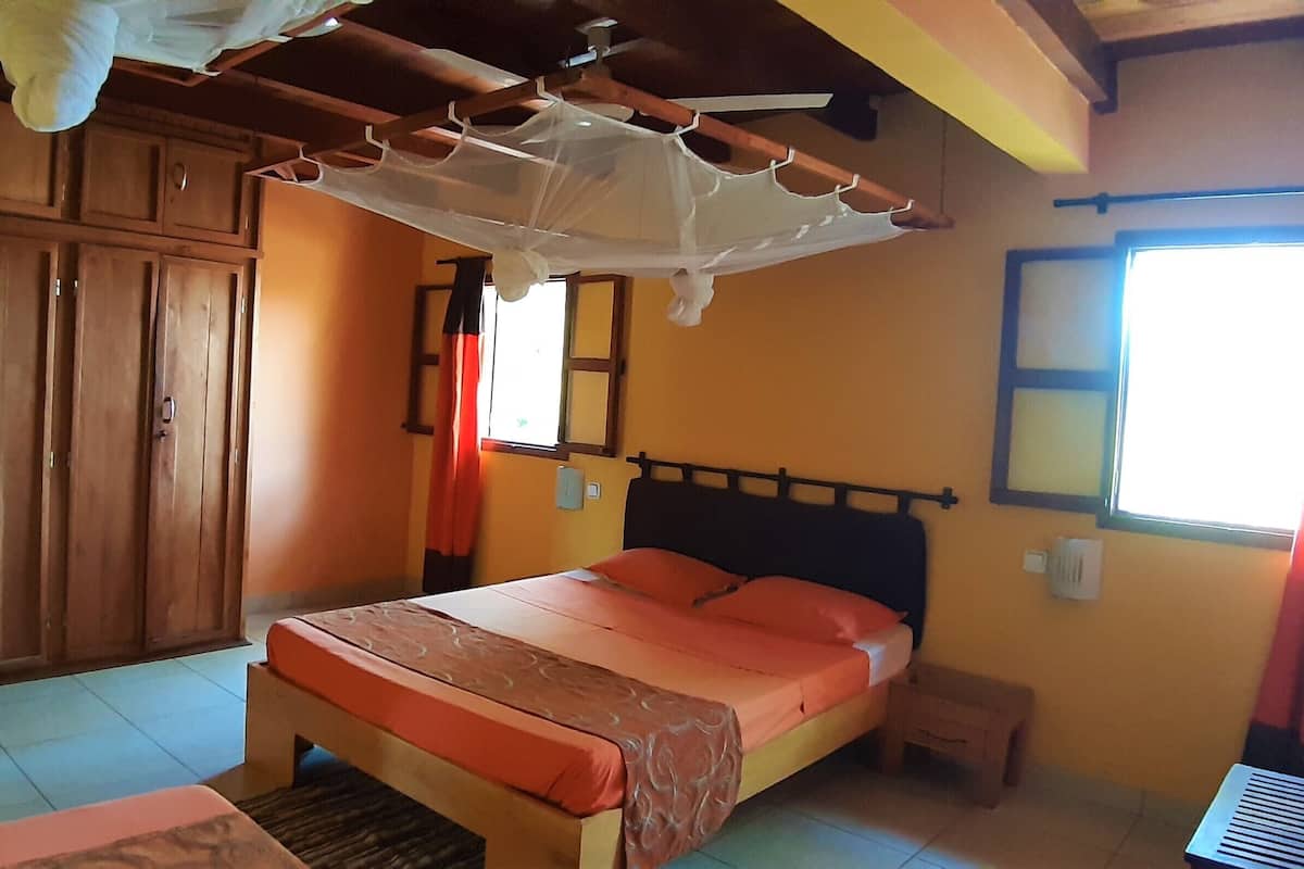 Un dormitorio con cama, armario de madera y ventilador de techo.
