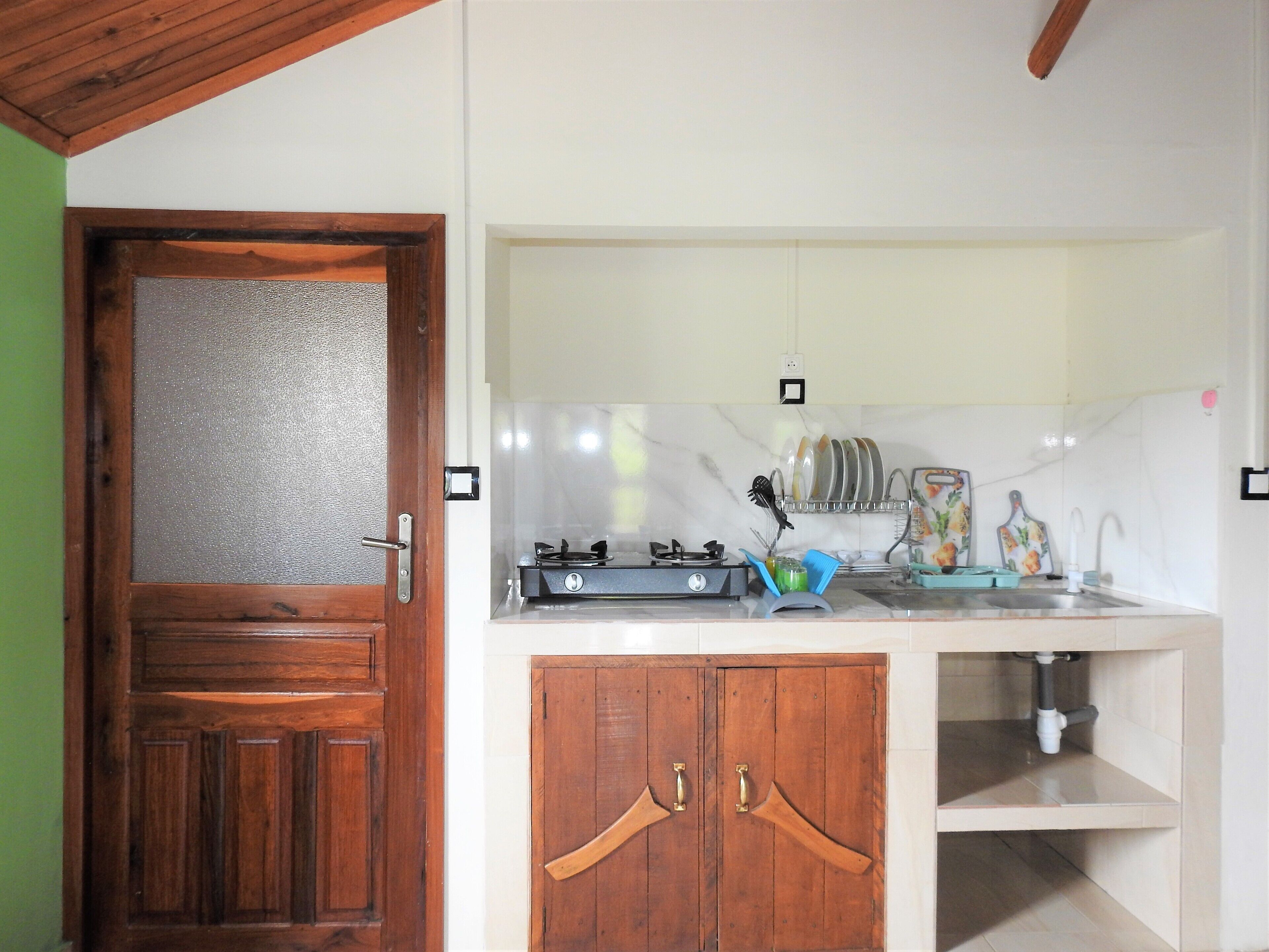 Une cuisine avec une porte en bois, une cuisinière à gaz et un évier.