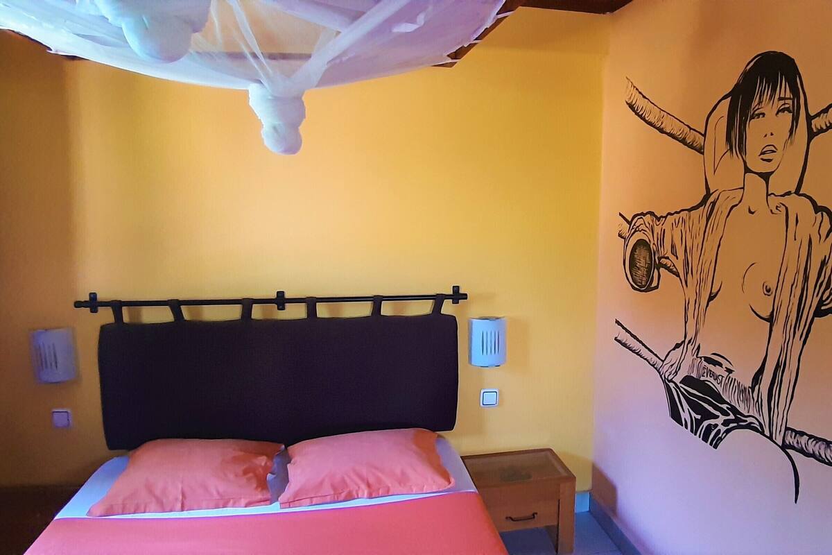 Un dormitorio con una cama, mesitas de noche y un mural en la pared.