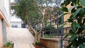 Un sendero de piedra que conduce a un edificio con barandilla metálica y follaje.