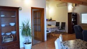 Un comedor con una mesa, sillas, una planta en maceta y un mueble de madera con vajilla.