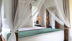 A room with a bed covered by a canopy, a bedside table with a lamp, and a wooden headboard. - The Mugatiya (Ahangama)