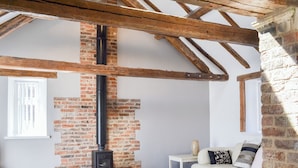 A room with exposed wooden beams, a brick fireplace, a white sofa, and a small table with a vase. - 3 bedroom accommodation in Flamborough (Flamborough)