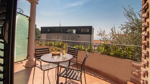 A balcony with a round table, chairs, and a bottle of wine. - Levantin Inn 1-3 Room N3 Sea Side (Sveti Stefan)