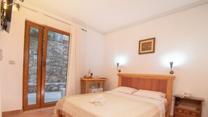 A bedroom with a bed, a nightstand, a lamp, a picture on the wall, and a sliding glass door leading to an outdoor area.