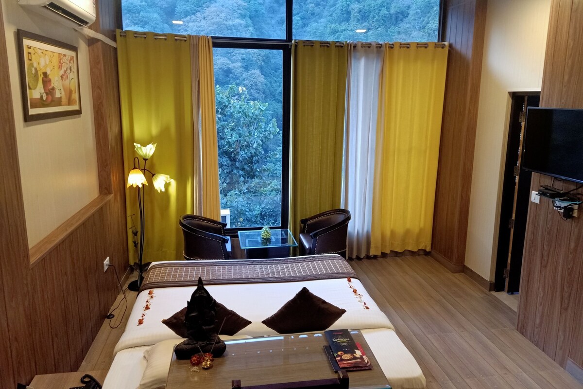 A hotel room with a bed, a desk, a chair, a TV, and a large window with curtains.