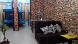Un salon avec un canapé marron, une table à manger et un mur orné d’un motif.