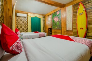 A hotel room with two beds, wooden walls, a surfboard, and a floral painting. - OYO 867 Bettah Coba Homestay (Cikakak)