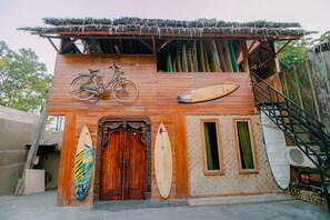 A wooden building with a bicycle and surfboards displayed outside. - OYO 867 Bettah Coba Homestay (Cikakak)