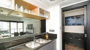 A modern kitchen with a double sink, wooden shelves, and a large mirror. - Al Majara 5 by Deluxe Holiday Homes (Dubai)
