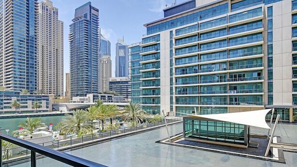 A modern hotel with a rooftop pool, surrounded by high-rise buildings and palm trees. - Al Majara 5 by Deluxe Holiday Homes (Dubai)