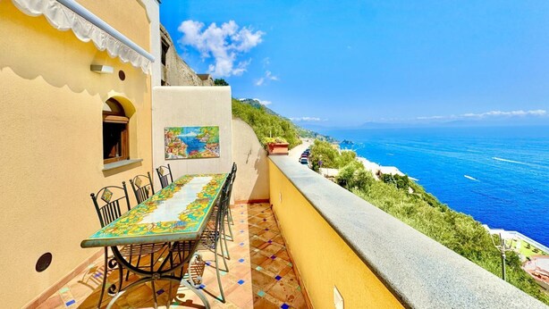 Un balcone con tavolo e sedie, vista sulla costa.