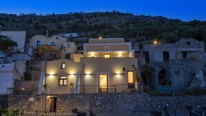 Un edificio a più piani con facciata in pietra, diversi balconi e un ingresso ben illuminato.
