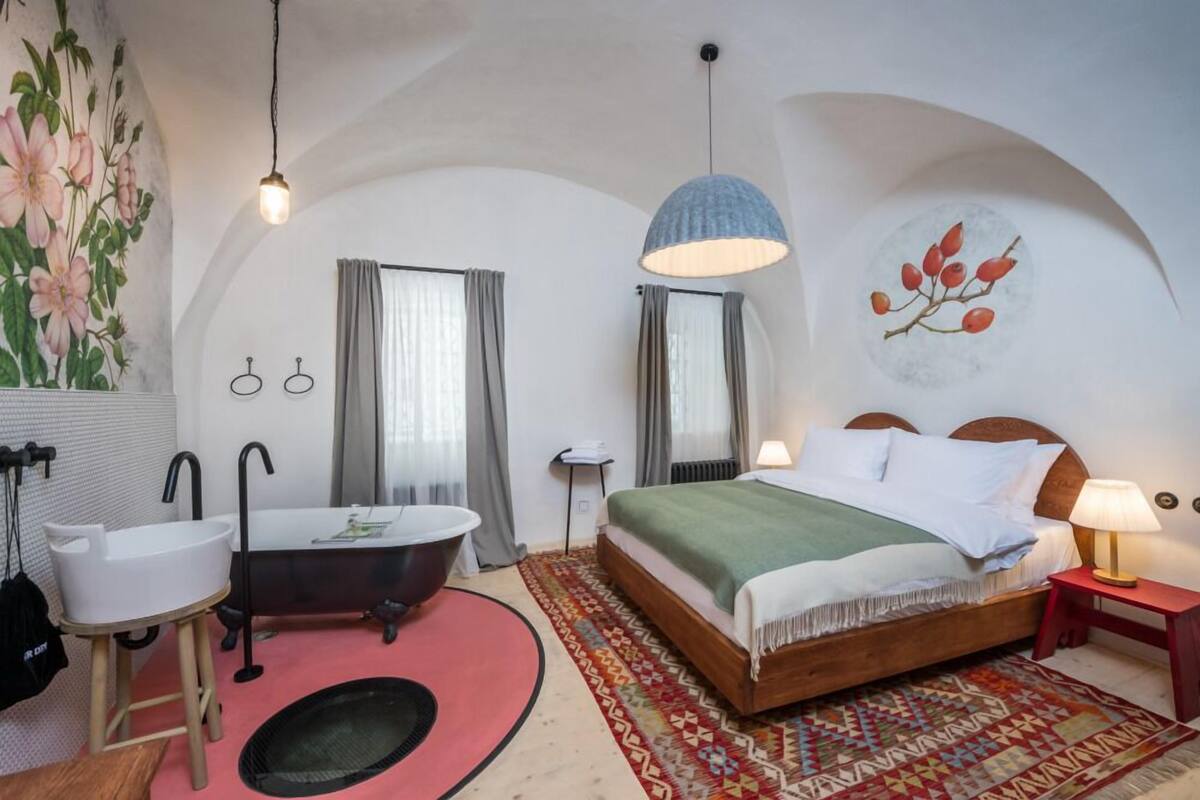 Un dormitorio con cama, bañera, lavamanos y espejo.