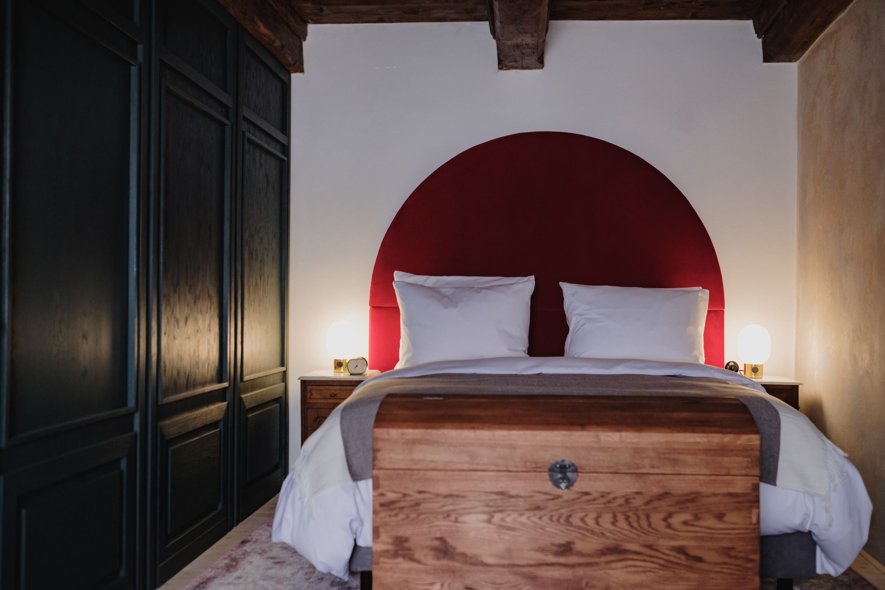 A bedroom with a wooden bed, a red arch headboard, and bedside lamps.