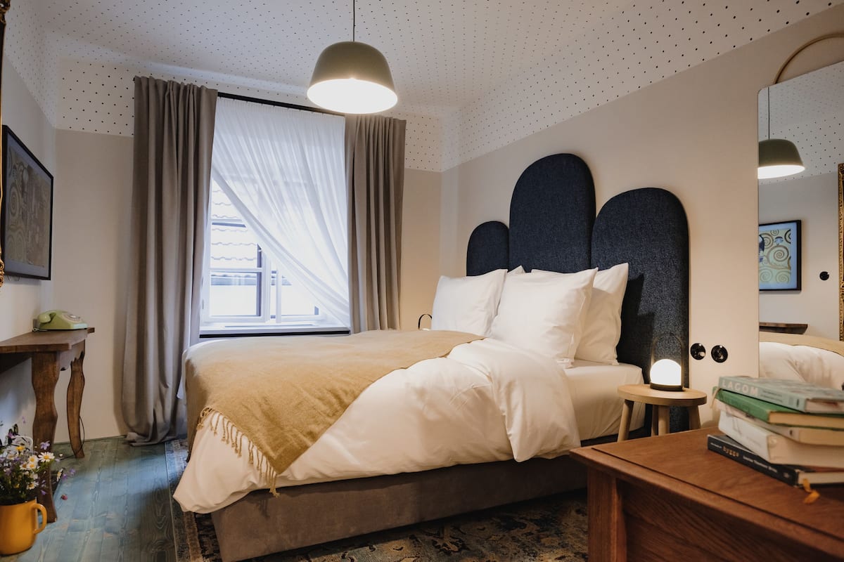 Un dormitorio ordenado con cama, mesita de noche y lámpara.