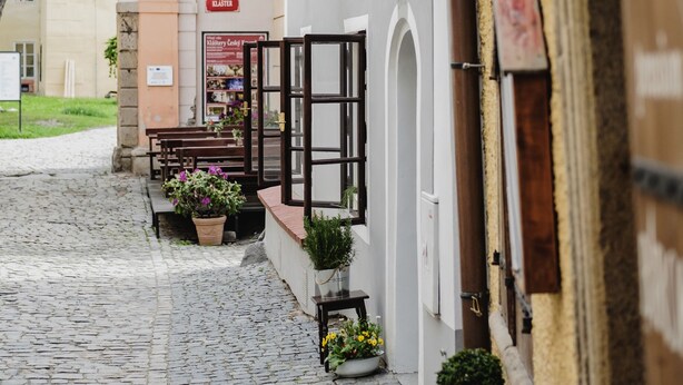 Una calle adoquinada con un edificio que muestra un letrero con la palabra 'ELSTER' y una bandera.