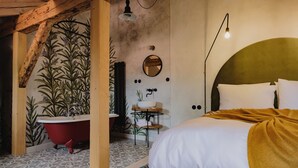 Un dormitorio con cama, una bañera roja, un espejo y un lavamanos.